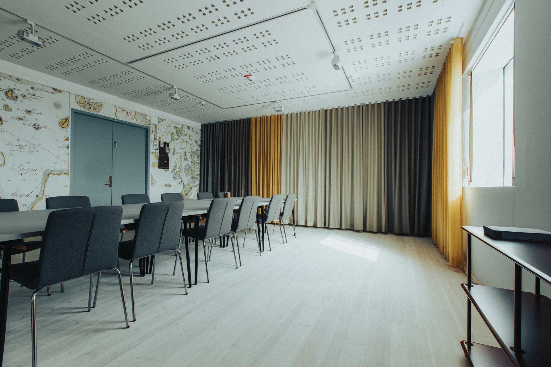 konferensrum med sjökarta på väggen och stora fönster. Gråa stolar och vitt bord.