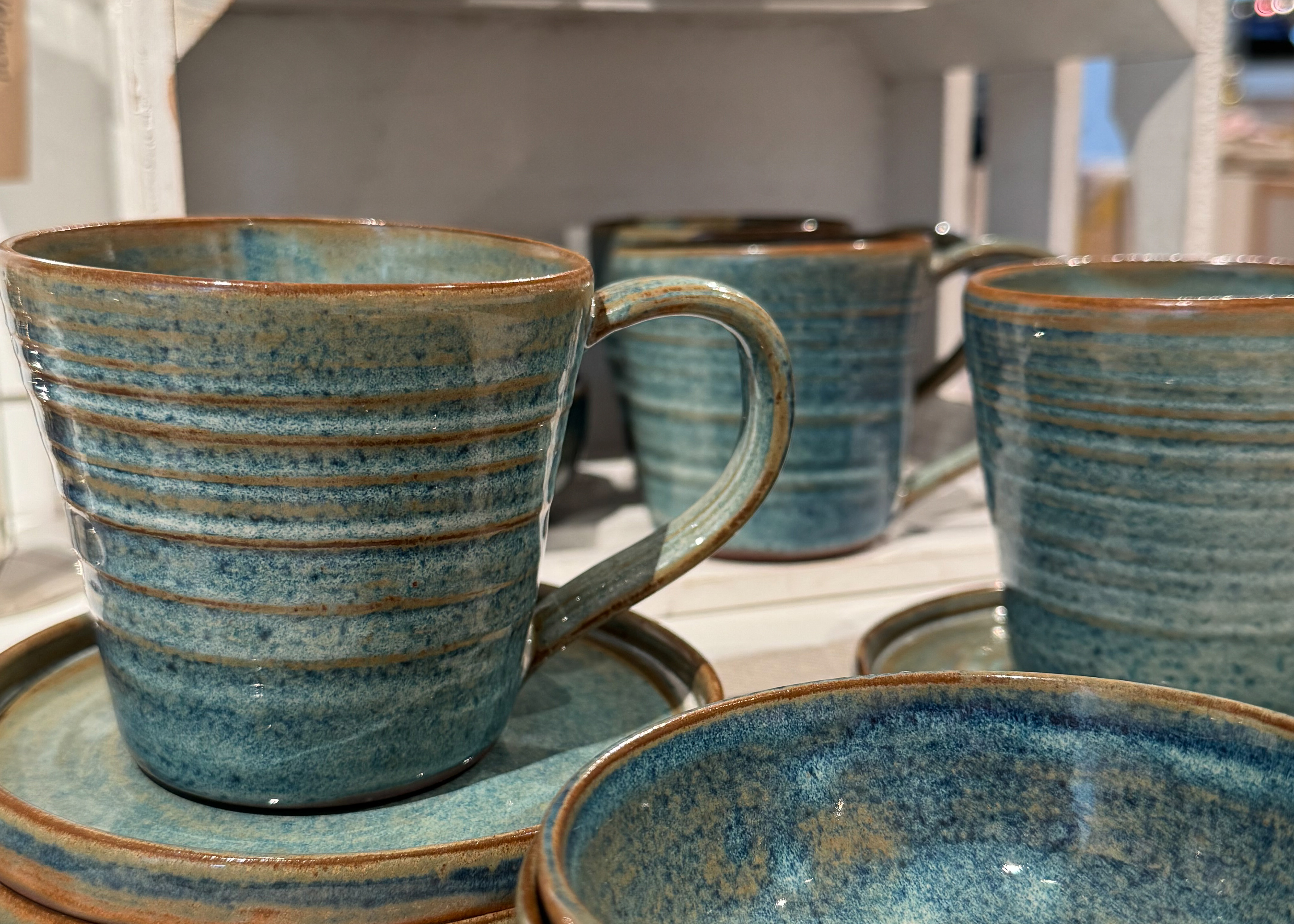 Närbild av blå och bruna keramikmuggar med fat i museibutiken på Marinmuseum.