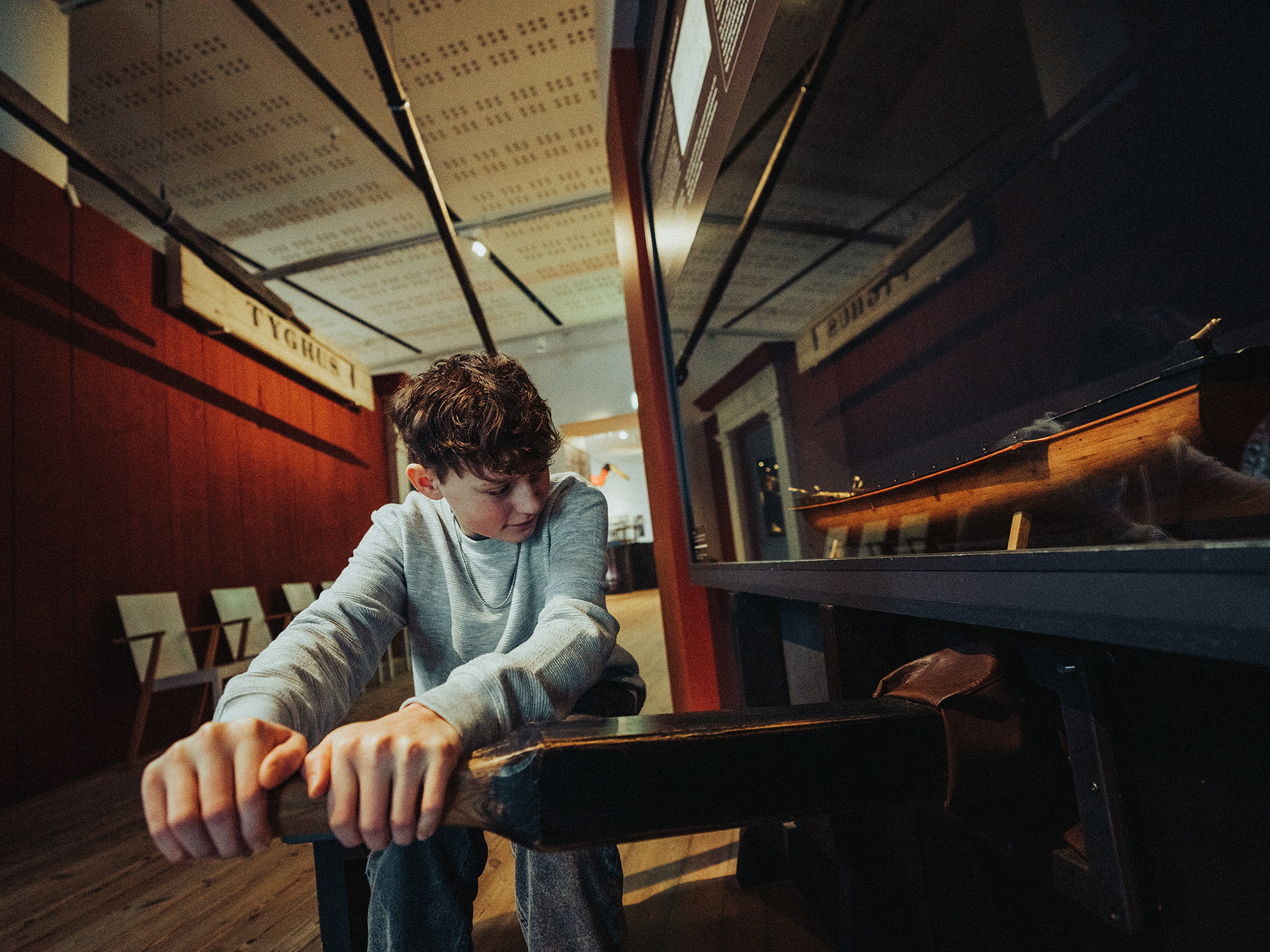 Ett barn provar en interaktiv aktivitet på Marinmuseum genom att dra i en stor åra för att känna hur tungt det är att ro.