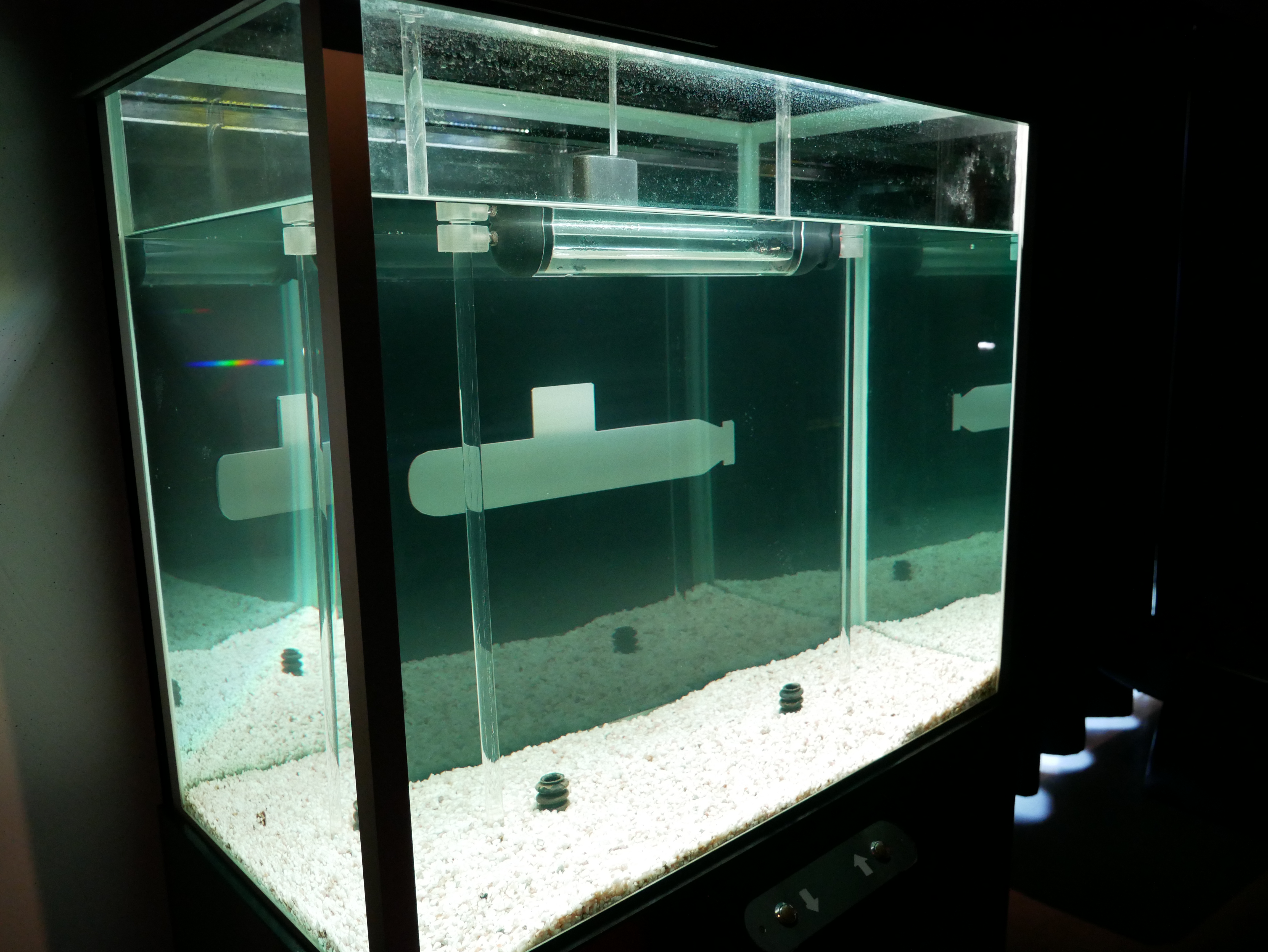 Interaktiv aktivitet i ett vattenfyllt glasakvarium på Marinmuseum som visar hur en ubåt rör sig under ytan.
