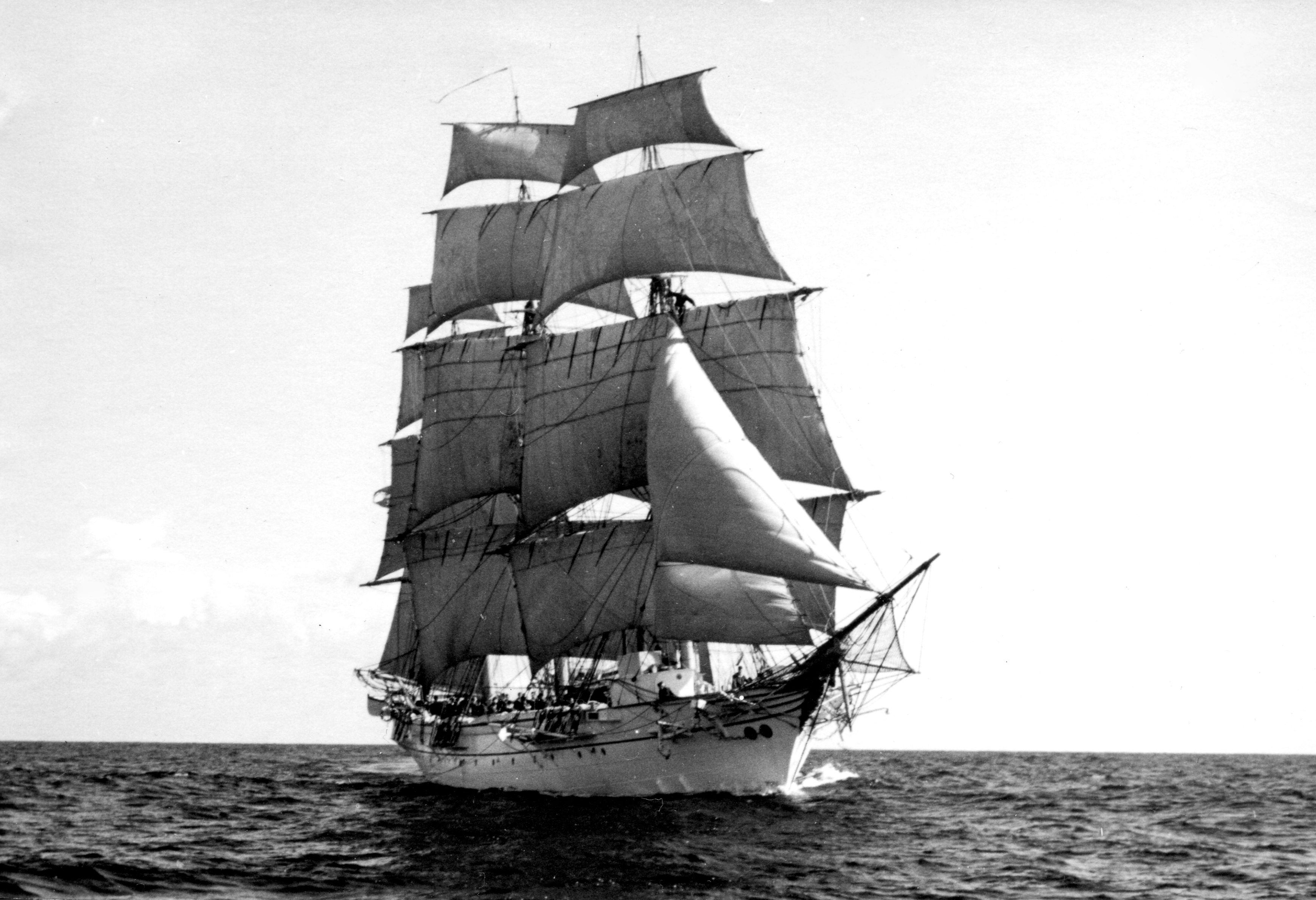 Segelfartyget "Jarramas" till havs med alla segel satta. Fartyget syns i helfigur från fören, seglen är fyllda av vind och besättningsmedlemmar syns längs relingen.