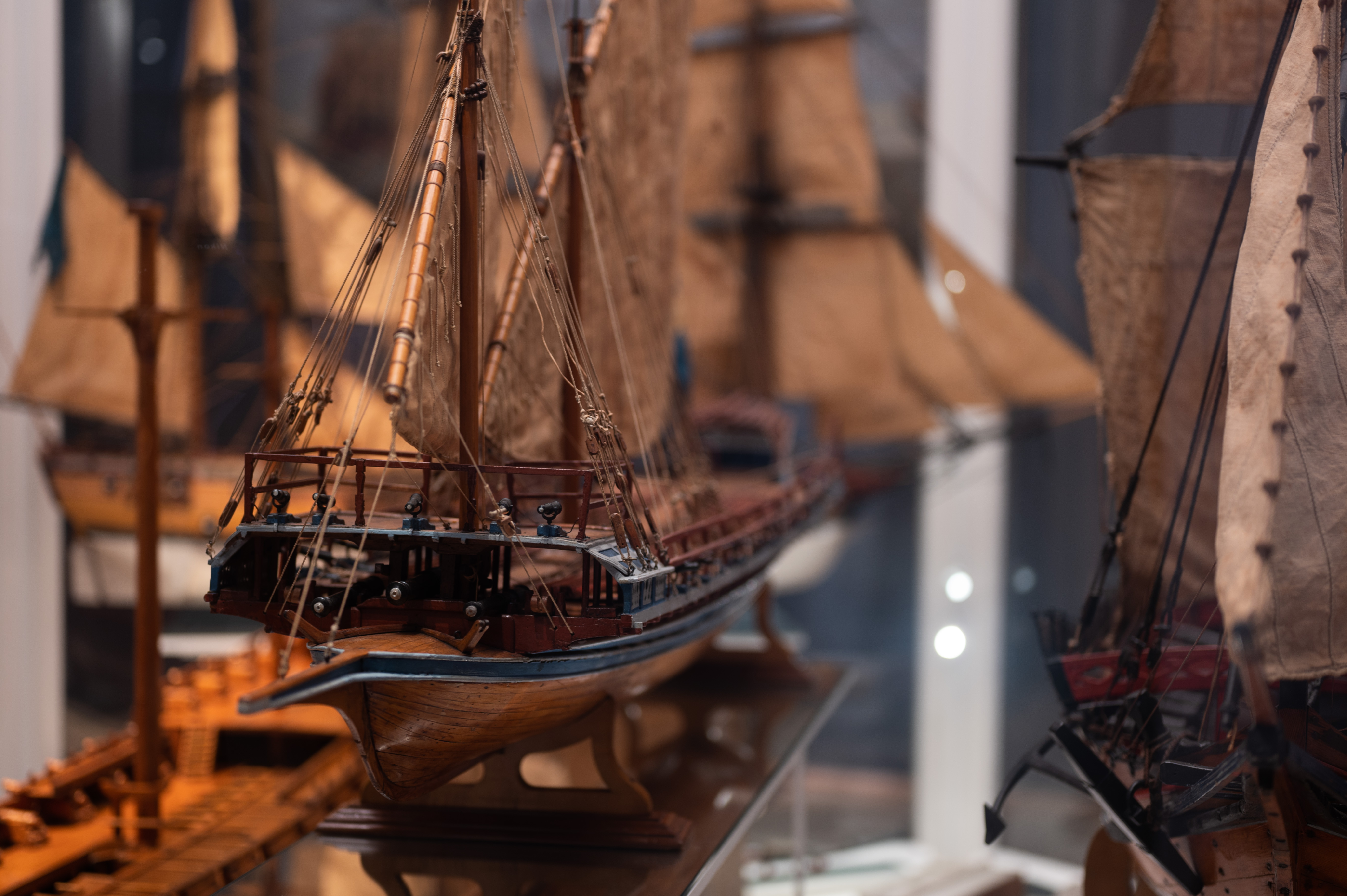 Close-up of a wooden model of a warship with white sails.