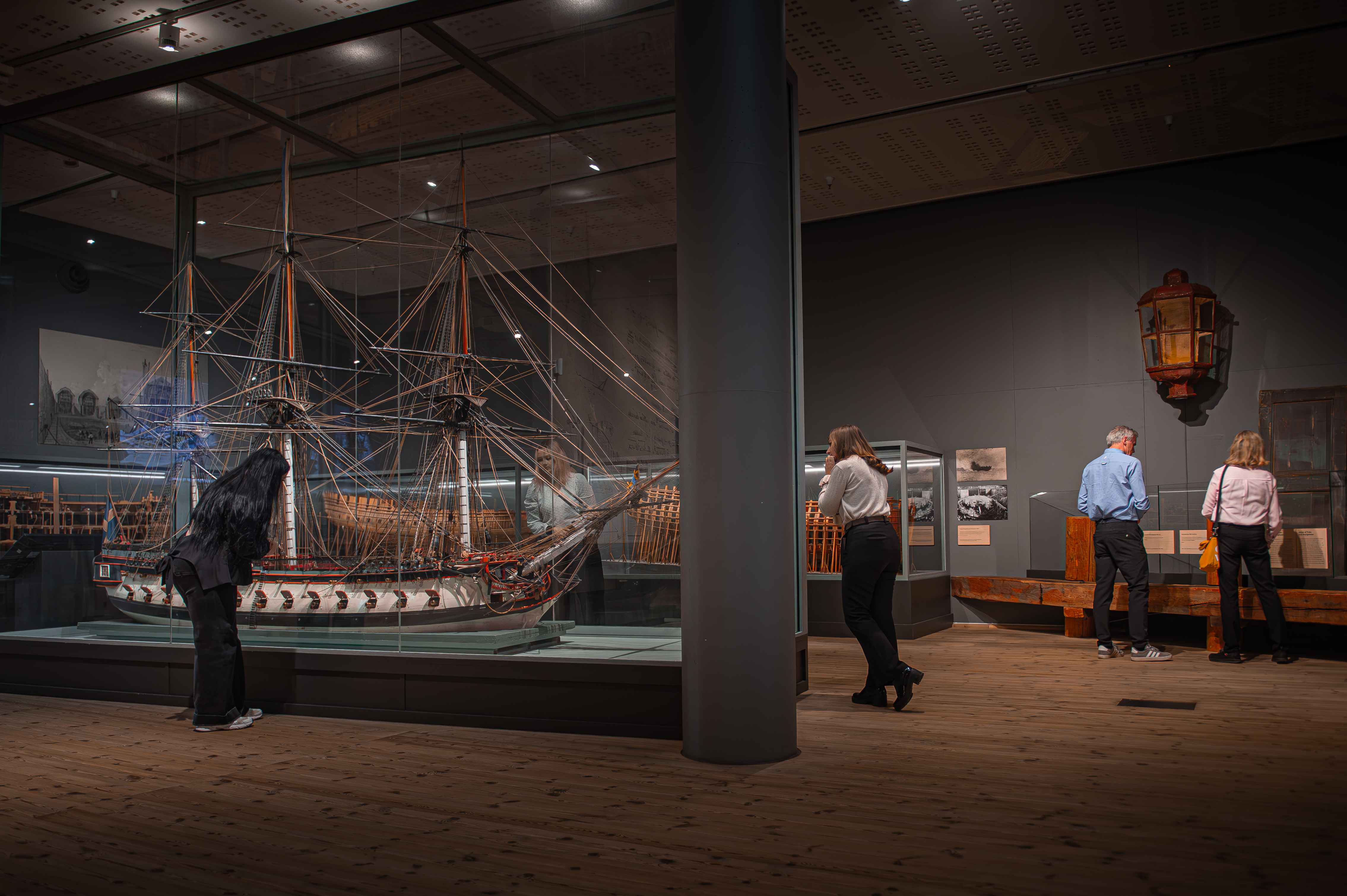 Besökare ser historiska skeppsmodeller och föremål i utställningen Skepp & folk på Marinmuseum.