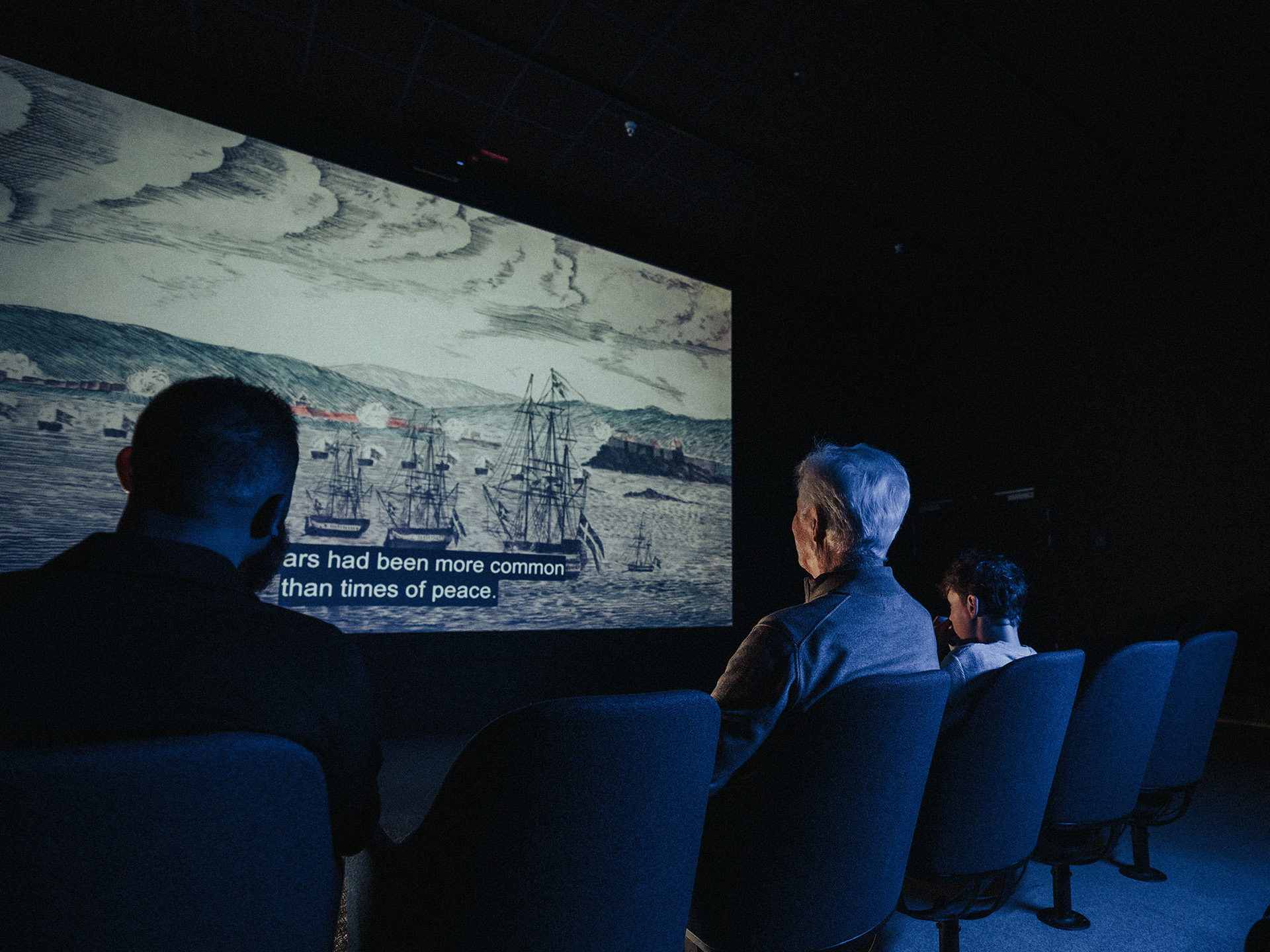 Besökare tittar på en filmvisning om flottans historia i en biosalong på Marinmuseum.