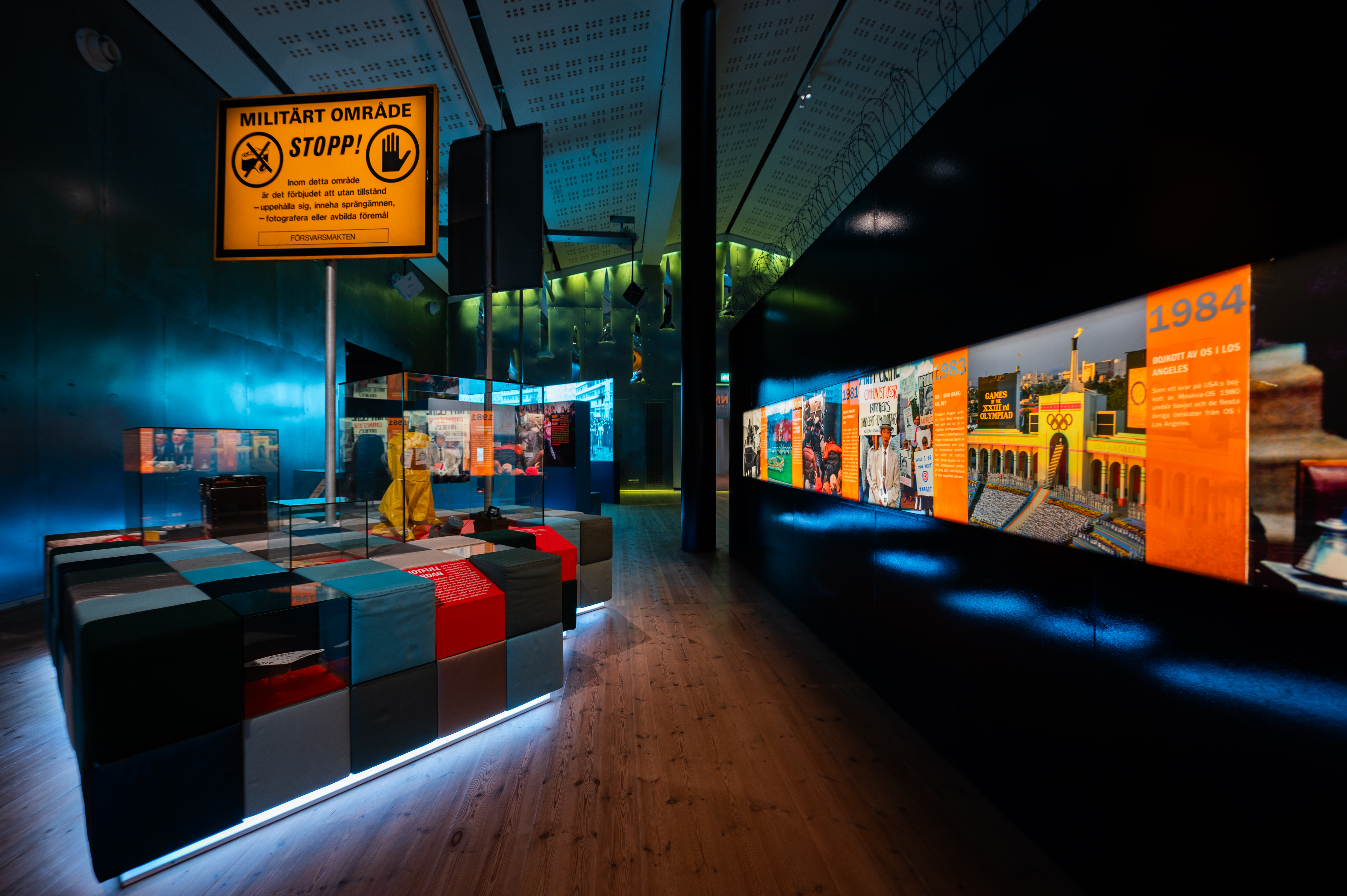 Large showroom with wooden floors and dim lighting. Glass display cases and orange signs are located in the room.