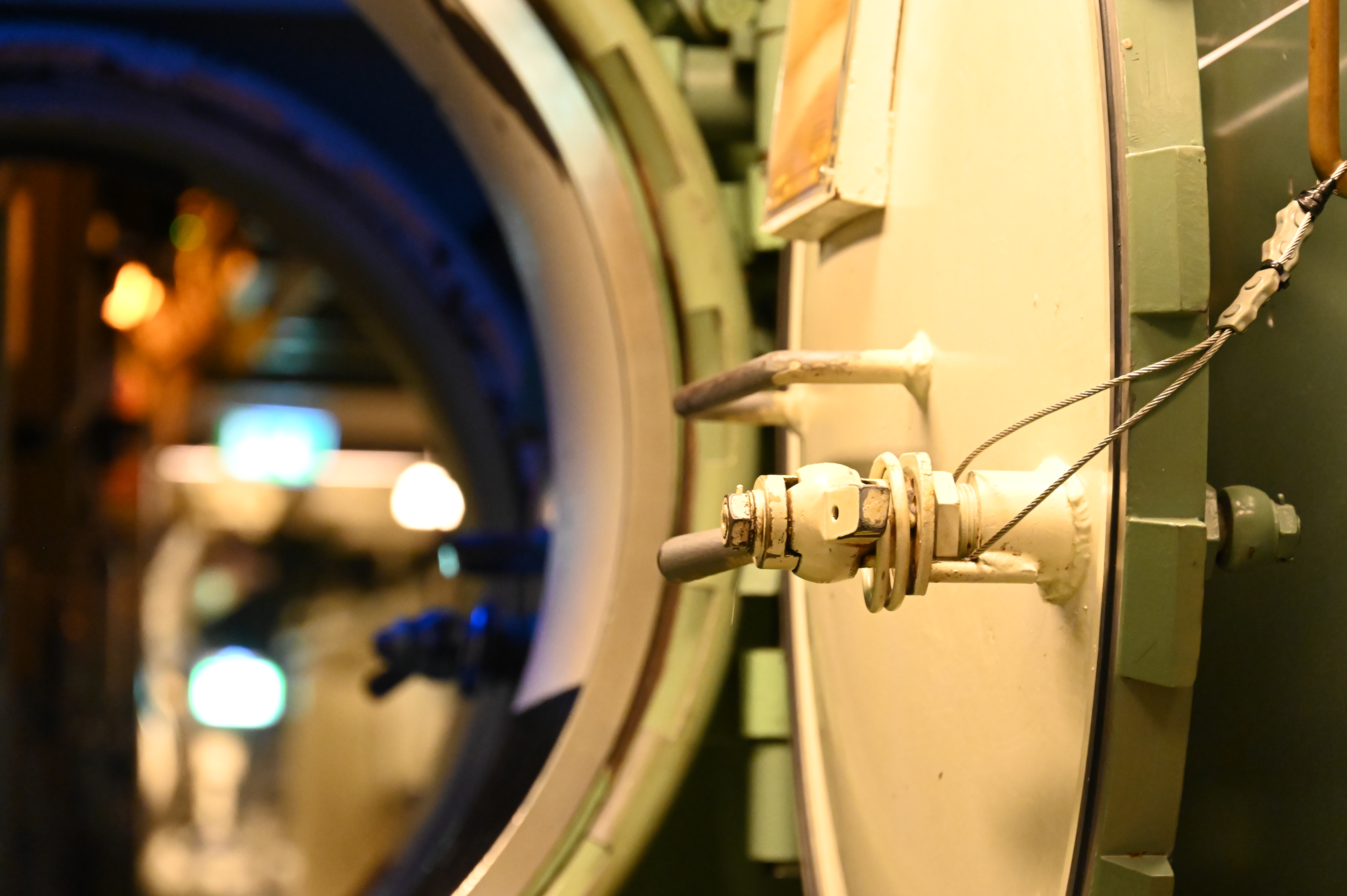Närbild på en rund ubåtslucka med metallhandtag och bultar, fotograferad inne i ubåten HMS Neptun på Marinmuseum.