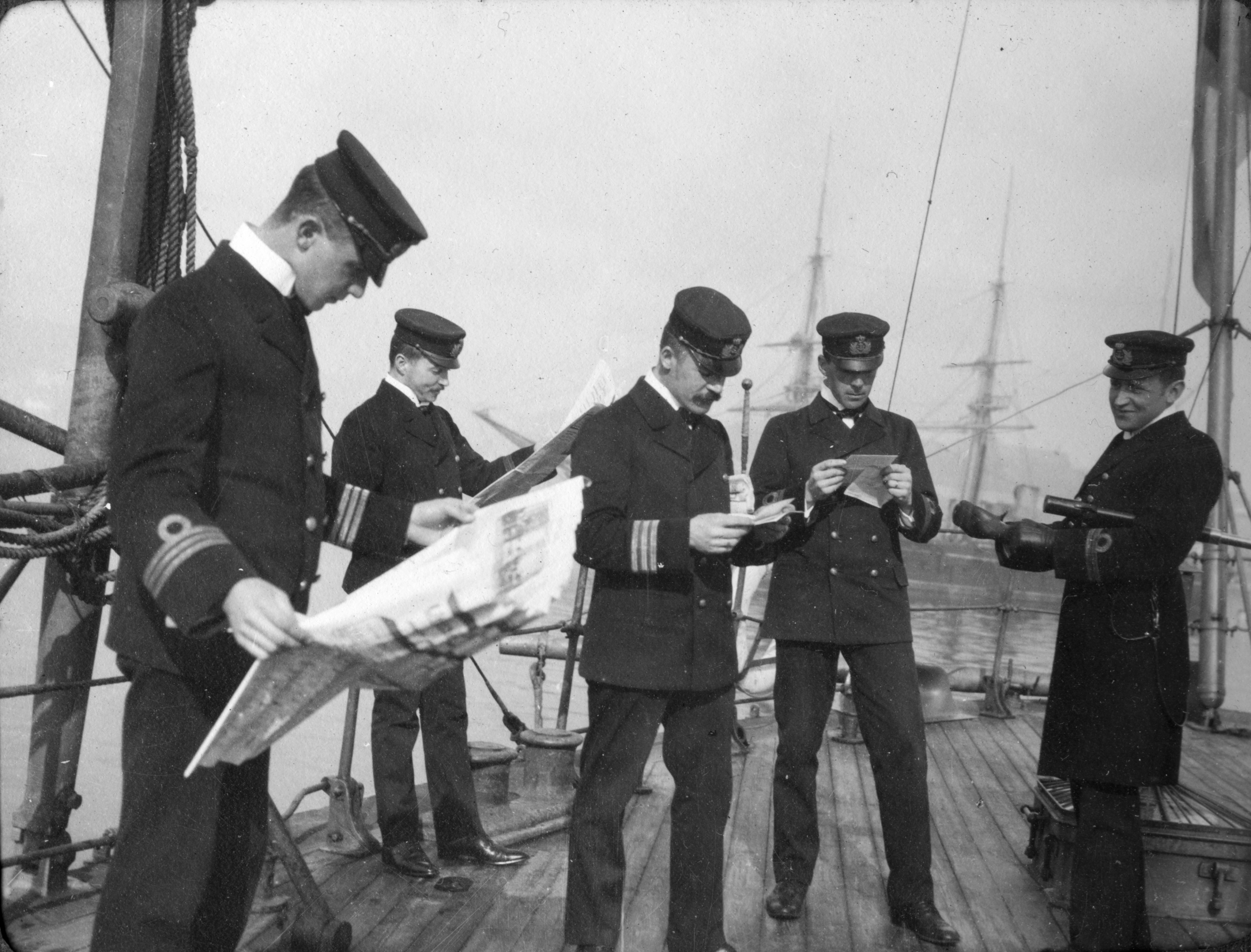 Marinofficerare ombord på ett fartyg läser brev och tidningar.