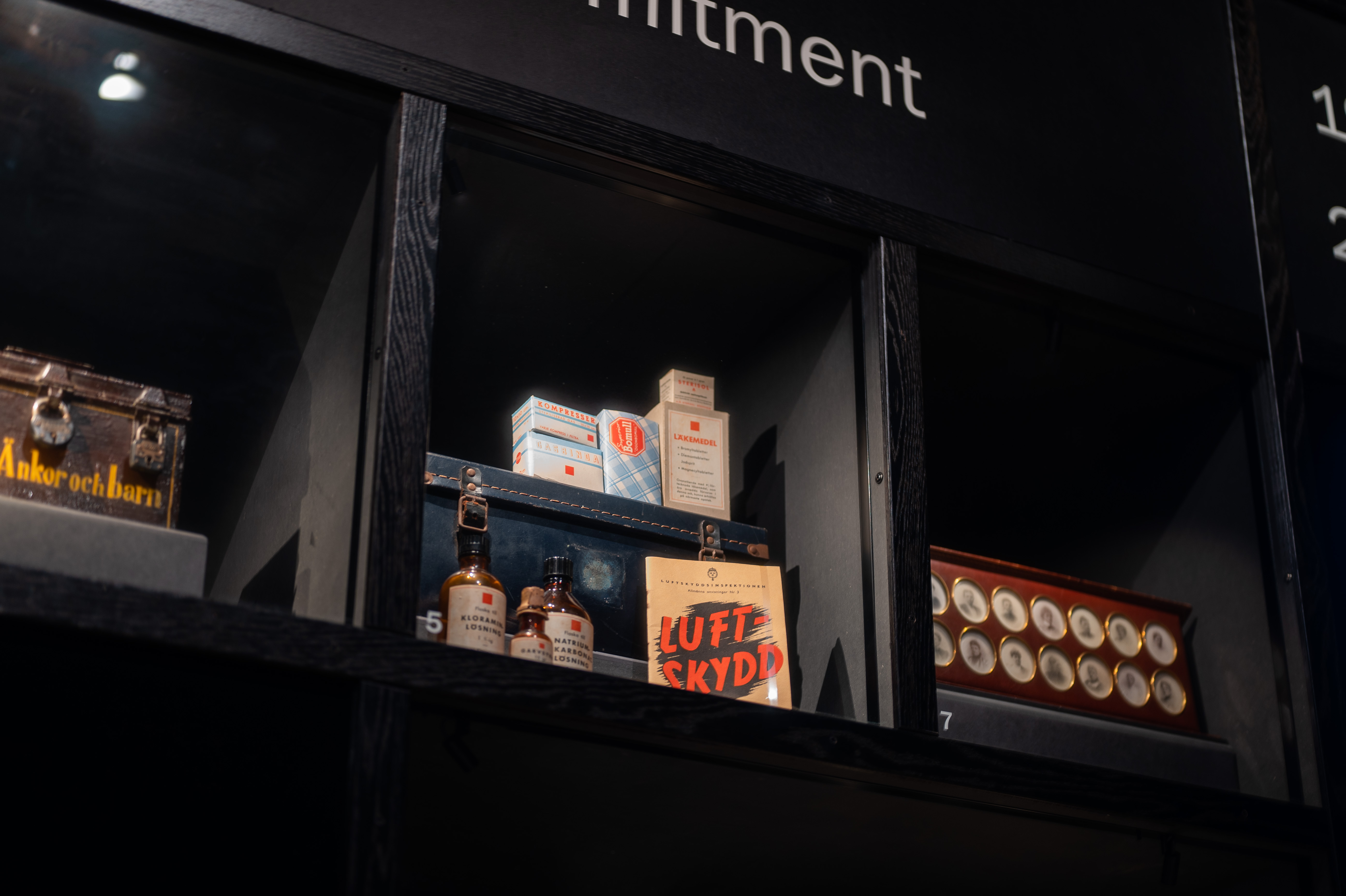 Föremål i en monter på Marinmuseum, bland annat flaskor och en skylt märkt ”Luftskydd”.