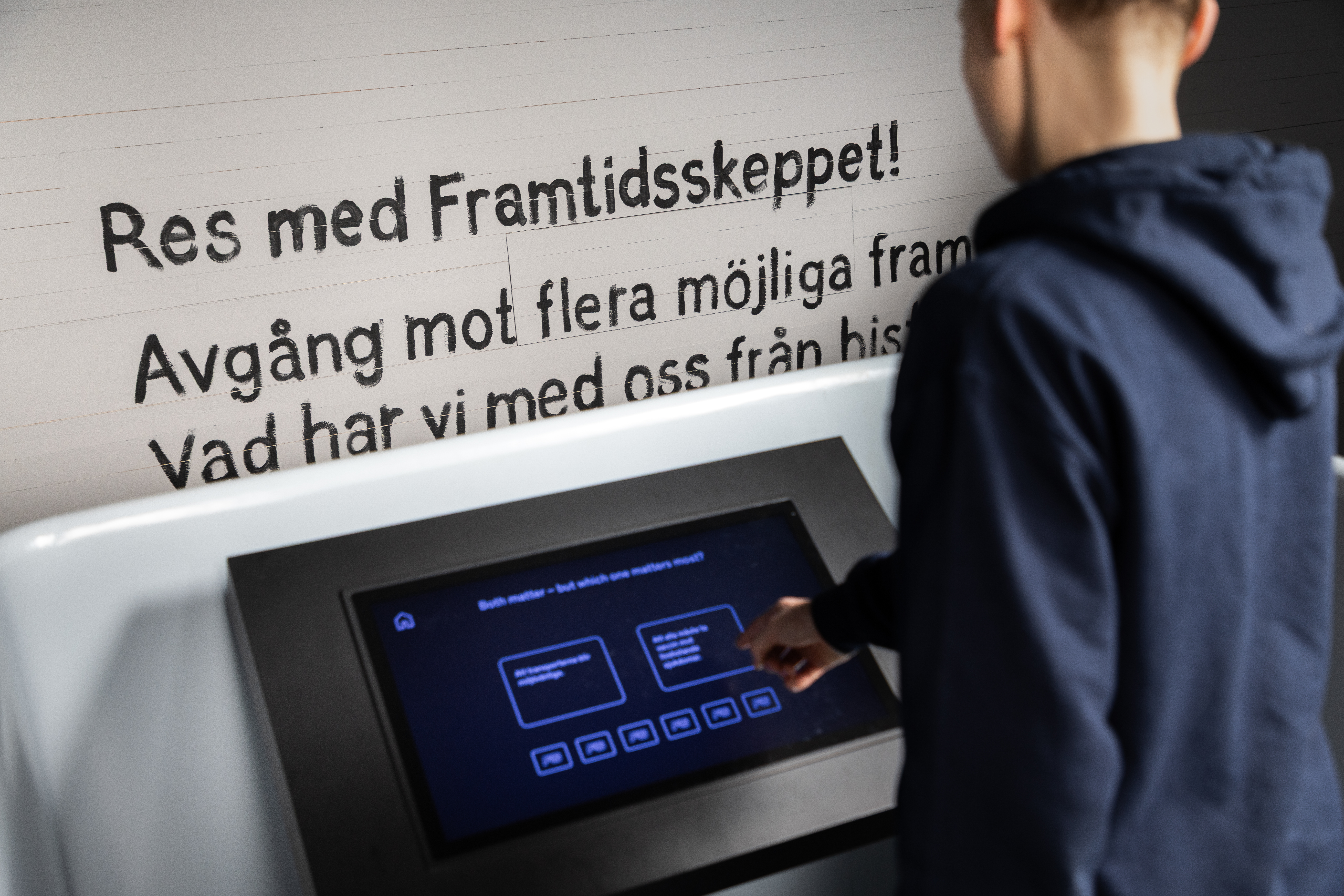 En ungdom använder en interaktiv pekskärm i utställningen Framtidsskeppet på Marinmuseum.